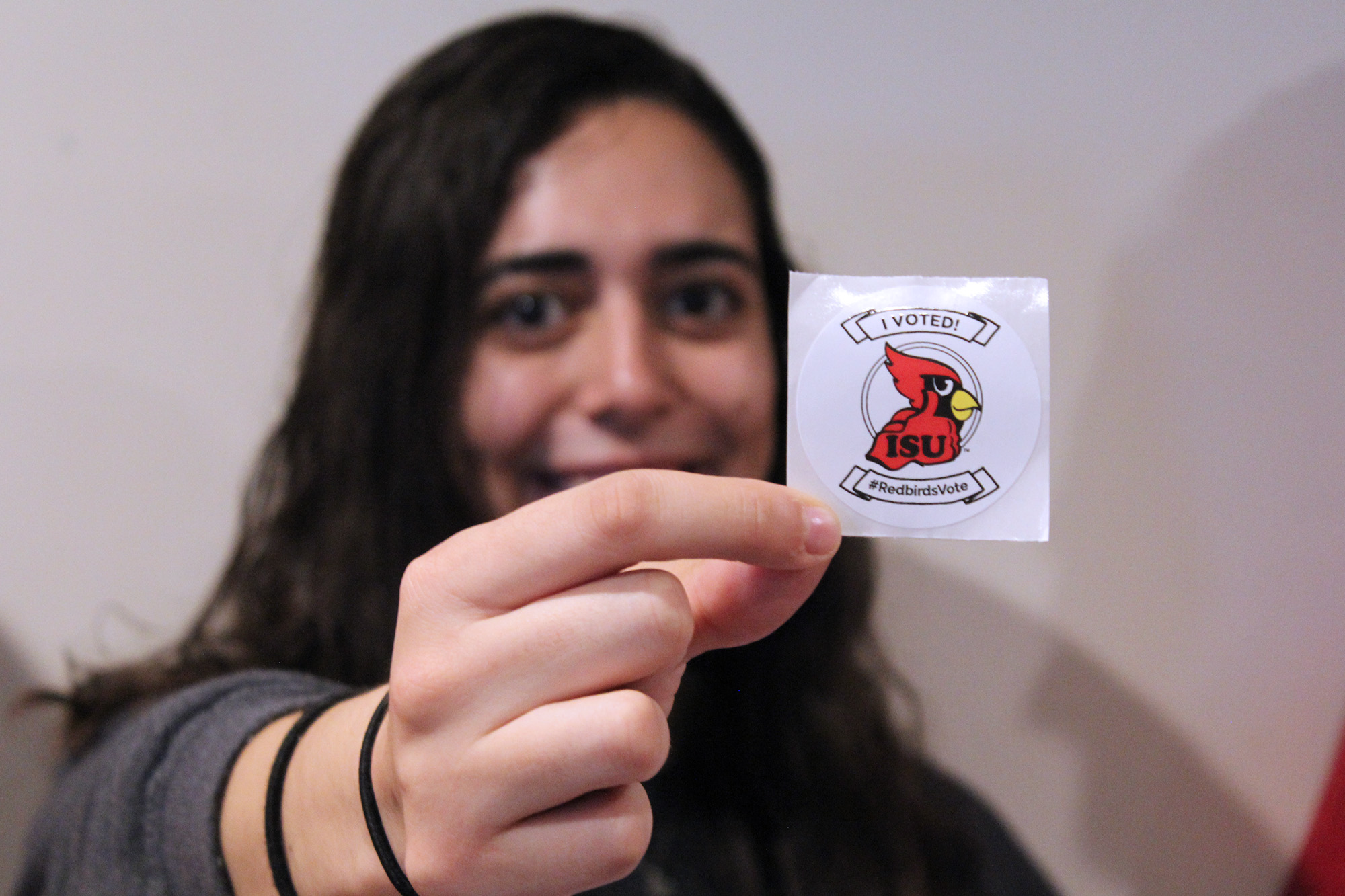 ISU student holding a Reggie Redbird voting sticker